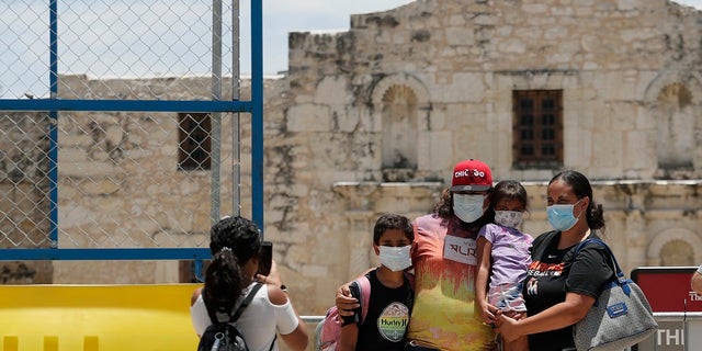 Visitors wearing masks to protect against the spread of COVID-19 pose for photos at the Alamo, which remains closed, in San Antonio last month. Cases of COVID-19 have spiked in Texas to over 200,000, according to government figures. (AP Photo/Eric Gay)