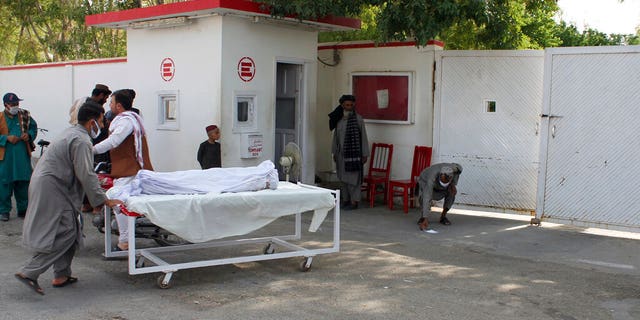 The body of a man who was killed during a deadly attack is moved on a gurney, in the southern Helmand province, Monday, June 29, 2020. A car bombing and mortar shells fired at a busy market in Helmand province on Monday killed over 20 people, including children, a statement from a provincial governor's office said. (AP Photo/Abdul Khaliq)