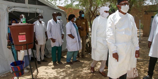 In this photo taken Thursday, May 21, 2020, a delegation led by Mali's Minister of Health Michel Sidibe, right, visits the isolation tent for patients with the coronavirus in Timbuktu, Mali. COVID-19 has made its way to Timbuktu, a town whose name has long been synonymous around the world with remoteness. (AP Photo/Baba Ahmed)