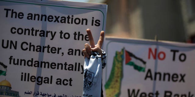 A Palestinian woman flashes the victory sign as she demonstrates against Israeli plans for the annexation of parts of the West Bank, in Gaza City, Wednesday, July 1, 2020. (AP Photo/Khalil Hamra)