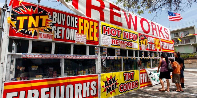 In this July 2, 2013, file photo, a family purchases fireworks at a TNT Fireworks stand in the City of Monterey Park, Calif. With fewer professional celebrations on July 4, 2020, due to the coronavirus pandemic, many Americans are bound to shoot off fireworks in backyards and at block parties. And they already are: Sales have been booming. (AP Photo/Nick Ut, File)