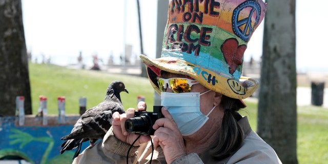 Métis - Vendor Vivianne Robinson, wearing a mask to protect from the coronavirus, takes a photo with a pigeon perched on her hand along the Venice Beach strand, Friday, July 3, 2020, in Los Angeles. (AP Photo/Richard Vogel)