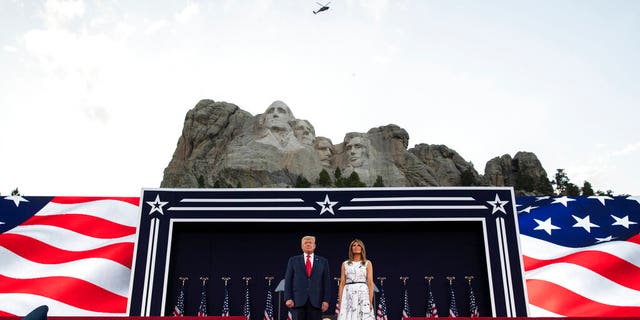 President Donald Trump, accompanied by first lady Melania Trump, stand during a flyover at Mount Rushmore National Memorial, Friday, July 3, 2020, near Keystone, S.D.