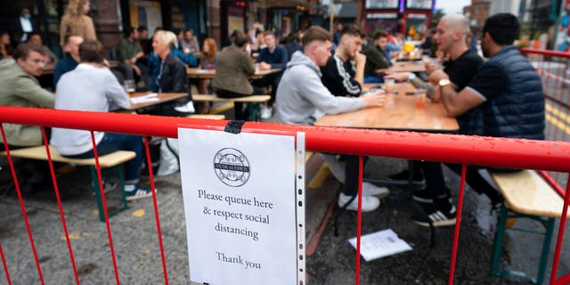 Members of the public are seen at a bar in Manchester's Northern Quarter, England, Saturday July 4, 2020. England is embarking on perhaps its biggest lockdown easing yet as pubs and restaurants have the right to reopen for the first time in more than three months Saturday. (AP Photo/Jon Super)