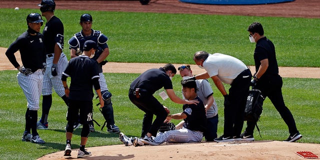 New York Yankees pitcher Masahiro Tanaka is tended to by team medical personnel after being hit by a ball off the bat of Yankees Giancarlo Stanton during a baseball a workout at Yankee Stadium in New York, Saturday, July 4, 2020. (Associated Press)