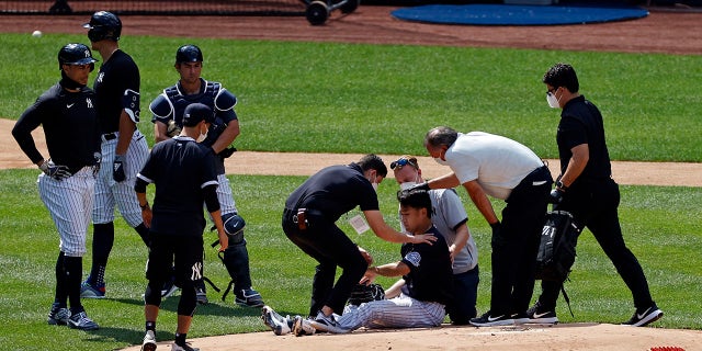 New York Yankees pitcher Masahiro Tanaka is tended to by team medical personnel after being hit by a ball off the bat of Yankees Giancarlo Stanton during a baseball a workout at Yankee Stadium in New York, Saturday, July 4, 2020. (Associated Press)
