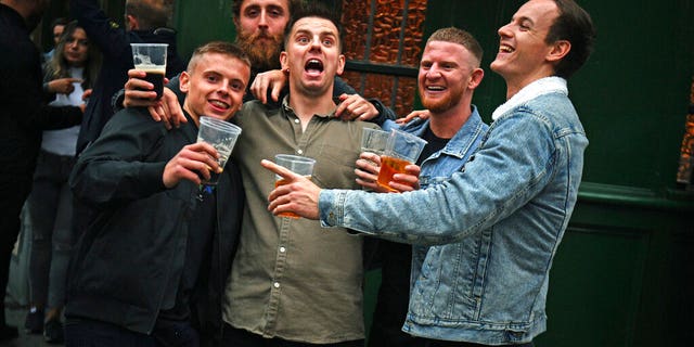 Men pose for a photo, outside a pub as it reopened, in Borough Market, as coronavirus lockdown restrictions eased across England, in London, Saturday, July 4, 2020. (Victoria Jones/PA via AP)
