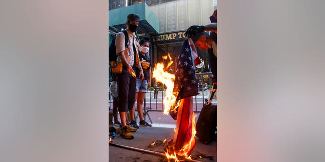 Protesters burn U.S. flags during a protest in front of Trump Tower on Fifth Avenue, Saturday, July 4, 2020, in New York.