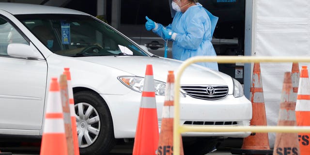 A health-care worker at a drive-through coronavirus testing site Sunday in Miami Gardens, Fla.