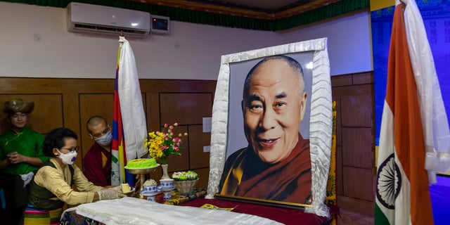 An exile Tibetan offers a piece of cake to a portrait of her spiritual leader the Dalai Lama to mark her leader's 85th birthday in Dharmsala, India, Monday, July 6, 2020. (AP Photo/Ashwini Bhatia)