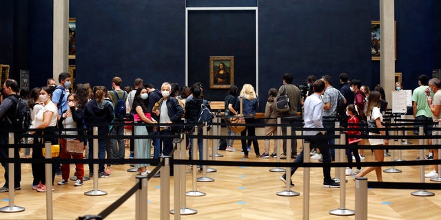 Visitors wait to see the Leonardo da Vinci's painting Mona Lisa, in Paris, Monday, July 6, 2020. The home of the world's most famous portrait, the Louvre Museum in Paris, reopened Monday after a four-month coronavirus lockdown. (AP Photo/ Thibault Camus)