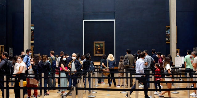 Visitors wait to see the Leonardo da Vinci's painting Mona Lisa, in Paris, Monday, July 6, 2020. The home of the world's most famous portrait, the Louvre Museum in Paris, reopened Monday after a four-month coronavirus lockdown. (AP Photo/ Thibault Camus)