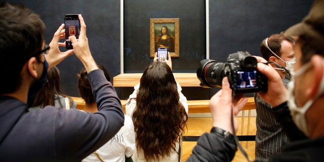 Visitors take photos of the Leonardo da Vinci's painting Mona Lisa, in Paris, Monday, July 6, 2020. The home of the world's most famous portrait, the Louvre Museum in Paris, reopened Monday after a four-month coronavirus lockdown. (AP Photo/ Thibault Camus)