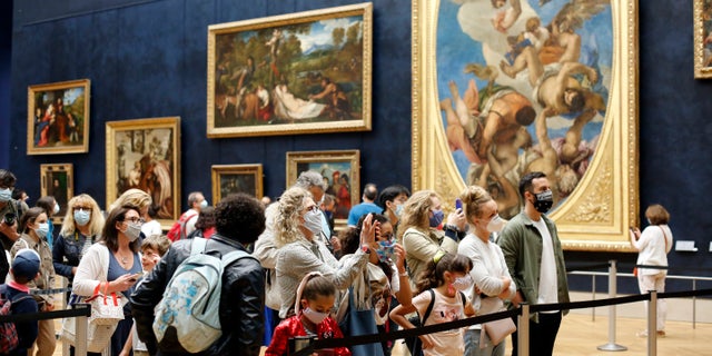 Visitors watch the Leonardo da Vinci's painting Mona Lisa, in Paris, Monday, July 6, 2020. The home of the world's most famous portrait, the Louvre Museum in Paris, reopened Monday after a four-month coronavirus lockdown. (AP Photo/ Thibault Camus)