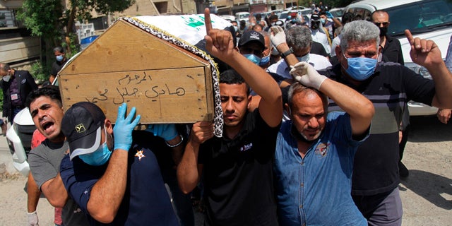 Mourners carry the flag-draped coffin of Hisham al-Hashimi during his funeral, in the Zeyouneh area of Baghdad, Iraq, Tuesday, July, 7, 2020. Al-Hashimi, an Iraqi analyst who was a leading expert on the Islamic State and other armed groups, was shot dead in Baghdad on Monday. (AP Photo/Khalid Mohammed)
