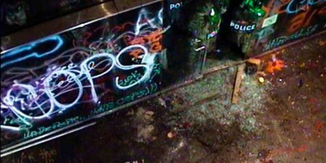 In this July 2, 2020 photo released by the U.S. Attorney Office in Oregon and taken from security cameras, officers with the Federal Protective Service can be seen, top right, holding their shields up and guarding the doorway of the Hatfield Federal Courthouse after the glass door shattered.. (U.S. Attorney's Office District of Oregon via AP)