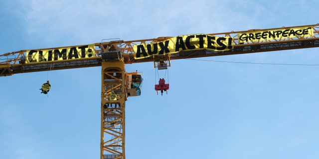 In this photo provided by Greenpeace, a banner attached to a crane reads: 