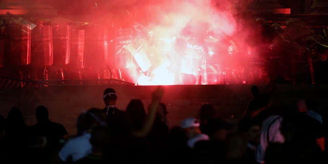 Protesters clash with riot police on the steps of the Serbian parliament during a protest in Belgrade, Serbia, Friday, July 10 2020. Hundreds of demonstrators tried to storm Serbia's parliament on Friday, clashing with police who fired tear gas during the fourth night of protests against the president's increasingly authoritarian rule. The protests started on Tuesday when President Aleksandar Vucic announced that Belgrade would be placed under a new three-day lockdown following a second wave of confirmed coronavirus infections. (AP Photo/Darko Vojinovic)