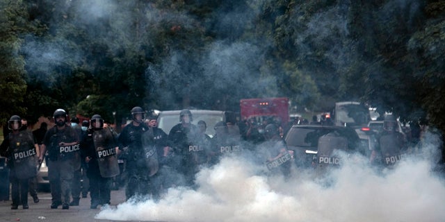 Detroit police stand in formation as protesters against police brutality march near where 20-year-old Hakeem Littleton was killed in a shootout with Detroit police earlier in the day on. An officer has been charged with in connection with shooting rubber bullets at three journalists days after George Floyd died, prosecutors said Monday. (Nicole Hester/Ann Arbor News via AP)