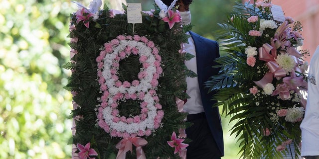 A man carries flowers into a viewing for 8-year-old Secoriea Turner, who was fatally shot in Atlanta on July 4th near the Wendy's site where Rayshard Brooks was killed the previous month. (AP Photo/John Bazemore)