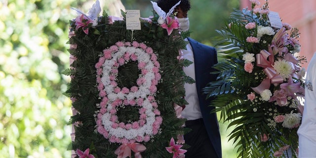 A man carries flowers into a viewing for 8-year-old Secoriea Turner, who was fatally shot in Atlanta on July 4th near the Wendy's site where Rayshard Brooks was killed the previous month. (AP Photo/John Bazemore)