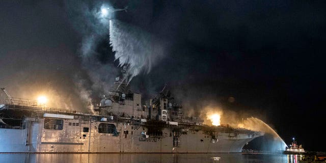 A helicopter from Helicopter Sea Combat Squadron (HSC) 3 combats a fire aboard the amphibious assault ship USS Bonhomme Richard (LHD 6) at Naval Base San Diego, Tuesday, July 14, 2020. 