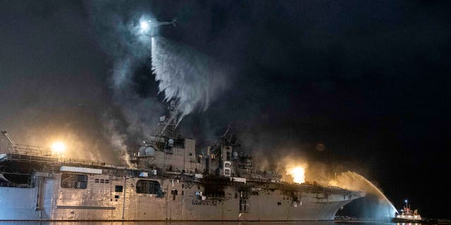 A helicopter from Helicopter Sea Combat Squadron (HSC) 3 combats a fire aboard the amphibious assault ship USS Bonhomme Richard (LHD 6) at Naval Base San Diego, Tuesday, July 14, 2020.