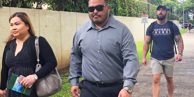 Former Honolulu police officer Reginald Ramones, center, walks down a street in Honolulu, on Sept. 25, 2019. (AP Photo/Jennifer Sinco Kelleher, File)