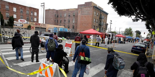 FILE: People line up to take a COVID-19 test in the Skid Row district in Los Angeles. 