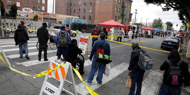 FILE: People line up to take a COVID-19 test in the Skid Row district in Los Angeles.