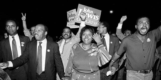 In this Tuesday night, Sept. 3, 1986, file photo, John Lewis, front left, and his wife, Lillian, holding hands, lead a march of supporters from his campaign headquarters to an Atlanta hotel for a victory party after he defeated Julian Bond in a runoff election for Georgia's 5th Congressional District seat in Atlanta.
