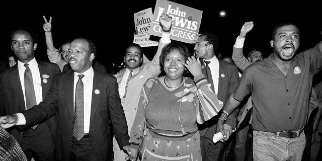 In this Tuesday night, Sept. 3, 1986, file photo, John Lewis, front left, and his wife, Lillian, holding hands, lead a march of supporters from his campaign headquarters to an Atlanta hotel for a victory party after he defeated Julian Bond in a runoff election for Georgia's 5th Congressional District seat in Atlanta.