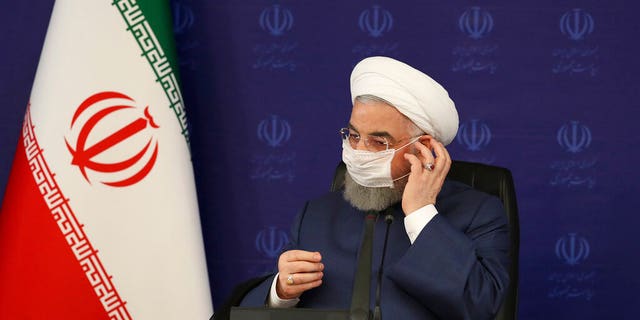 In this photo released by the official website of the office of the Iranian Presidency, President Hassan Rouhani adjusts his face mask in a meeting of the national headquarters of the fight against the COVID-19, in Tehran, Iran, Saturday, July 18, 2020. (Iranian Presidency Office via AP)