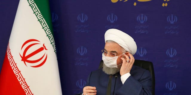 In this photo released by the official website of the office of the Iranian Presidency, President Hassan Rouhani adjusts his face mask in a meeting of the national headquarters of the fight against the COVID-19, in Tehran, Iran, Saturday, July 18, 2020. (Iranian Presidency Office via AP)