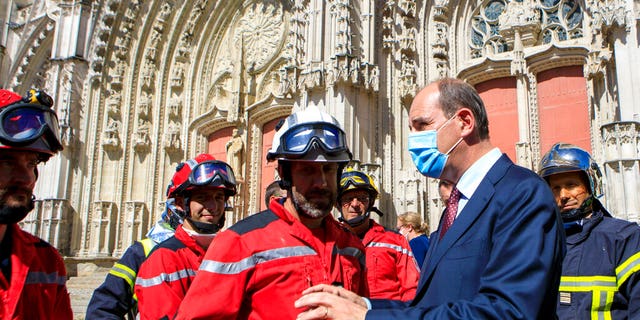 French Prime minister Jean Castex, right, wearing a face mask meets firefighters after the blaze at the Gothic St. Peter and St. Paul Cathedral, in Nantes, western France, Saturday, July 18, 2020.