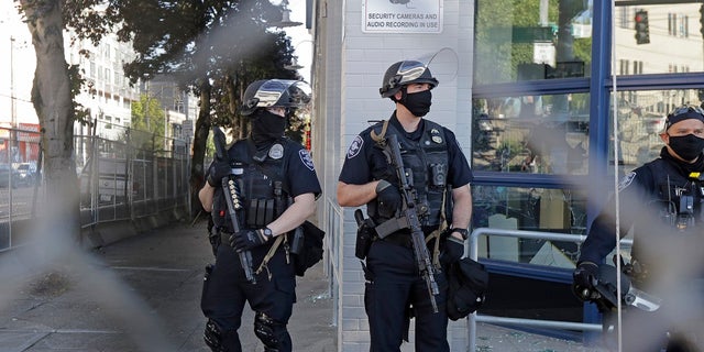 Seattle police officers hold weapons as they stand guard outside the East Precinct Building recently. (Associated Press)