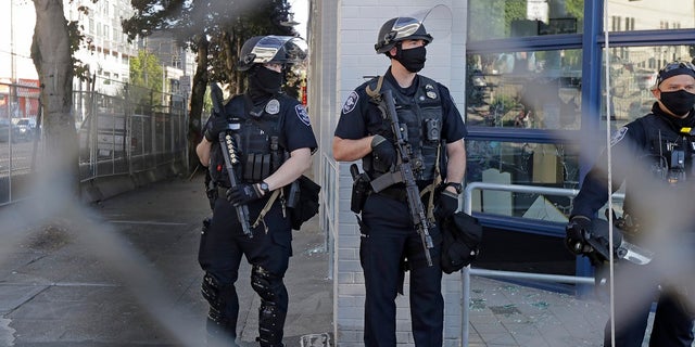 Seattle police officers hold weapons as they stand guard outside the East Precinct Building recently. (Associated Press)