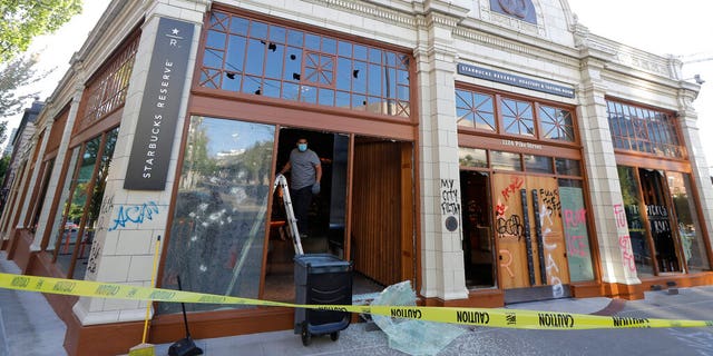 A worker clears glass from broken windows at the Starbucks Roastery, Sunday, July 19, 2020 in Seattle's Capitol Hill neighborhood. Protesters broke windows at the store earlier in the afternoon. (AP Photo/Ted S. Warren)