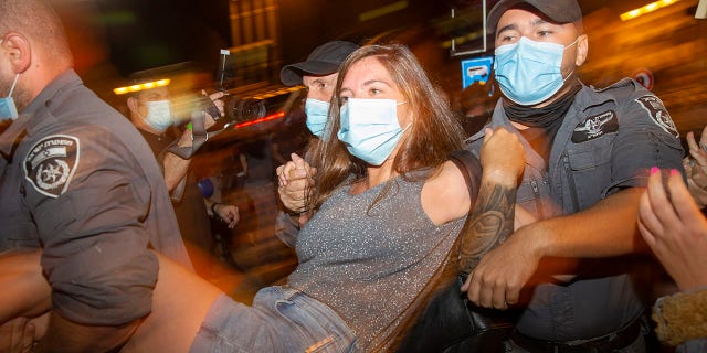 Israeli police officers arrest a demonstrator during a protest against Israel's Prime Minister Benjamin Netanyahu outside his residence in Jerusalem, early Friday, July 24, 2020. (Associated Press)