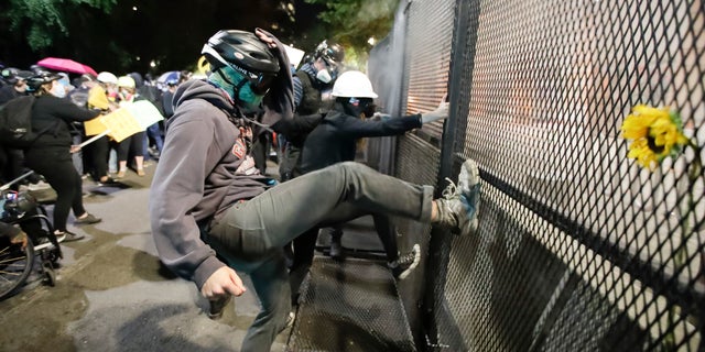 Demonstrators tried to kick down a fence during a Black Lives Matter protest at the Mark O. Hatfield United States Courthouse July 23, in Portland, Ore. (AP Photo/Marcio Jose Sanchez)
