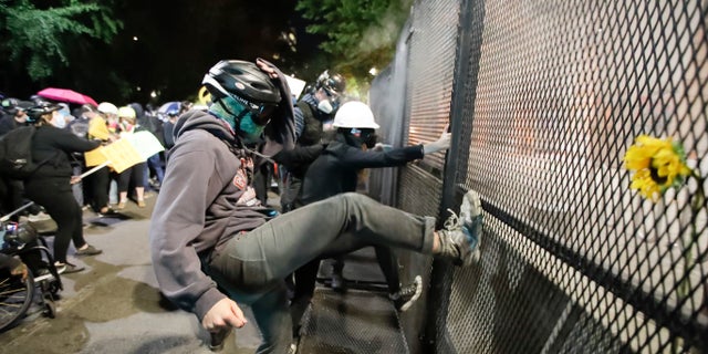 Demonstrators tried to kick down a fence during a Black Lives Matter protest at the Mark O. Hatfield United States Courthouse July 23, in Portland, Ore. (AP Photo/Marcio Jose Sanchez)