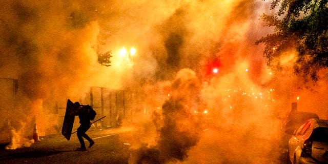 A Black Lives Matter protester uses a shield as federal officers use chemical irritants to disperse demonstrators at the Mark O. Hatfield United States Courthouse on Friday, July 24, 2020, in Portland, Ore. Since federal officers arrived in downtown Portland in early July, violent protests have largely been limited to a two block radius from the courthouse. 