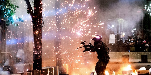 A federal officer firing crowd-control munitions outside the Mark O. Hatfield United States Courthouse last week in Portland, Ore. (AP Photo/Noah Berger)