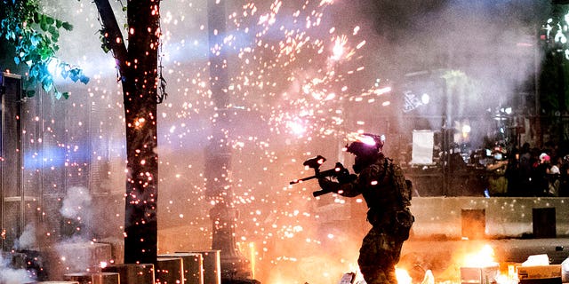 A federal officer fires crowd control munitions at Black Lives Matter protesters at the Mark O. Hatfield United States Courthouse on Friday, July 24, 2020, in Portland, Ore. Since federal officers arrived in downtown Portland in early July, violent protests have largely been limited to a two block radius from the courthouse.