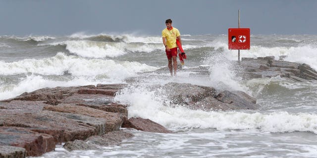 Galveston Island Beach Patrol lifeguard Matthew Herdrich walks along the rock groin at 39th Street in Galveston, Texas, as waves kicked up by Tropical Storm Hanna wash over it Friday, July 24, 2020. Officials in South Texas say they’re prepared to handle any challenges from Tropical Storm Hanna. The storm is headed their way and expected to make landfall this weekend. (Jennifer Reynolds/The Galveston County Daily News via AP)