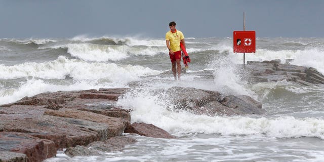 Galveston Island Beach Patrol lifeguard Matthew Herdrich walks along the rock groin at 39th Street in Galveston, Texas, as waves kicked up by Tropical Storm Hanna wash over it Friday, July 24, 2020. Officials in South Texas say they’re prepared to handle any challenges from Tropical Storm Hanna. The storm is headed their way and expected to make landfall this weekend. (Jennifer Reynolds/The Galveston County Daily News via AP)