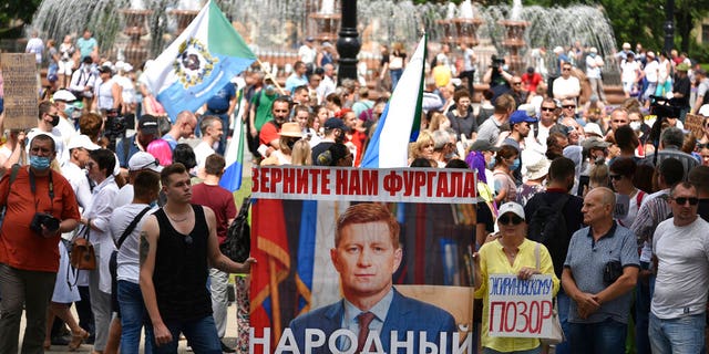 People hold posters reading "Give us back Sergei Furgal, people's governor " during an unsanctioned protest in support of Sergei Furgal, the governor of the Khabarovsk region, who was interrogated ordered held in jail for two months, in Khabarovsk, 3,800 miles east of Moscow, Russia, Saturday, July 25, 2020. Thousands of people in the Russian Far East city of Khabarovsk gather on Saturday, protesting the arrest of the region's governor on charges of involvement in multiple murders.