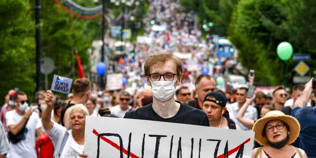 A man holds poster reading "Putinizm " during an unsanctioned protest in support of Sergei Furgal, the governor of the Khabarovsk region, who was interrogated and ordered held in jail for two months, in Khabarovsk, 6100 kilometers (3800 miles) east of Moscow, Russia, Saturday, July 25, 2020.