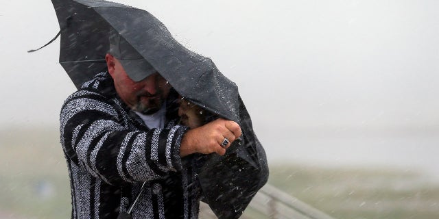 A man holds the front on his umbrella as he fights heavy rain and wind on Seawall Boulevard in Galveston, Texas, Saturday, July 25, 2020. (Associated Press)