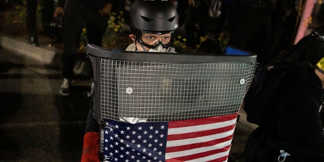 A protester holds a homemade riot shield during a protest in front of the Oakland Police Department Station on Saturday, July 25, 2020, in Oakland, Calif. (Associated Press)